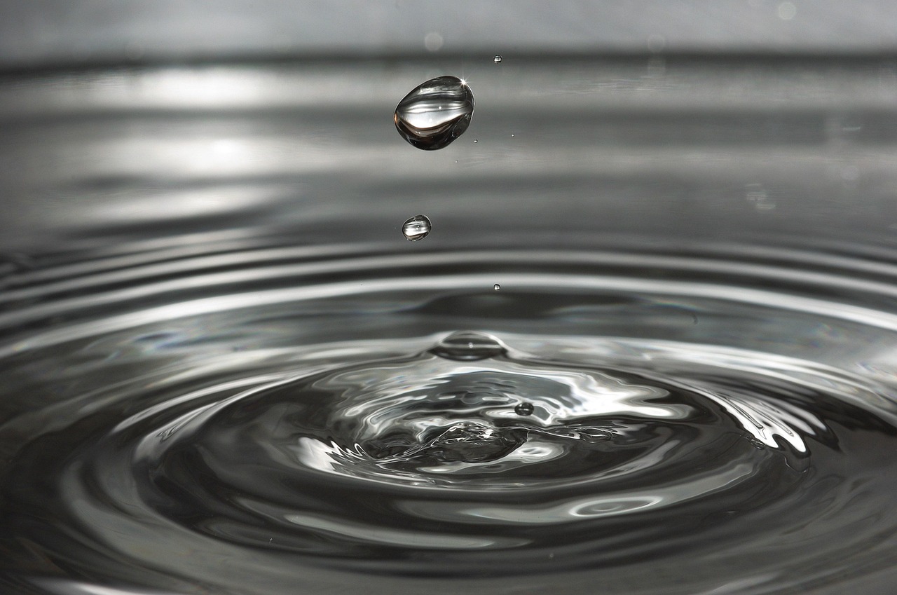 Illustration comparing water droplet shapes on Earth (elongated due to gravity) versus in microgravity (spherical due to surface tension).